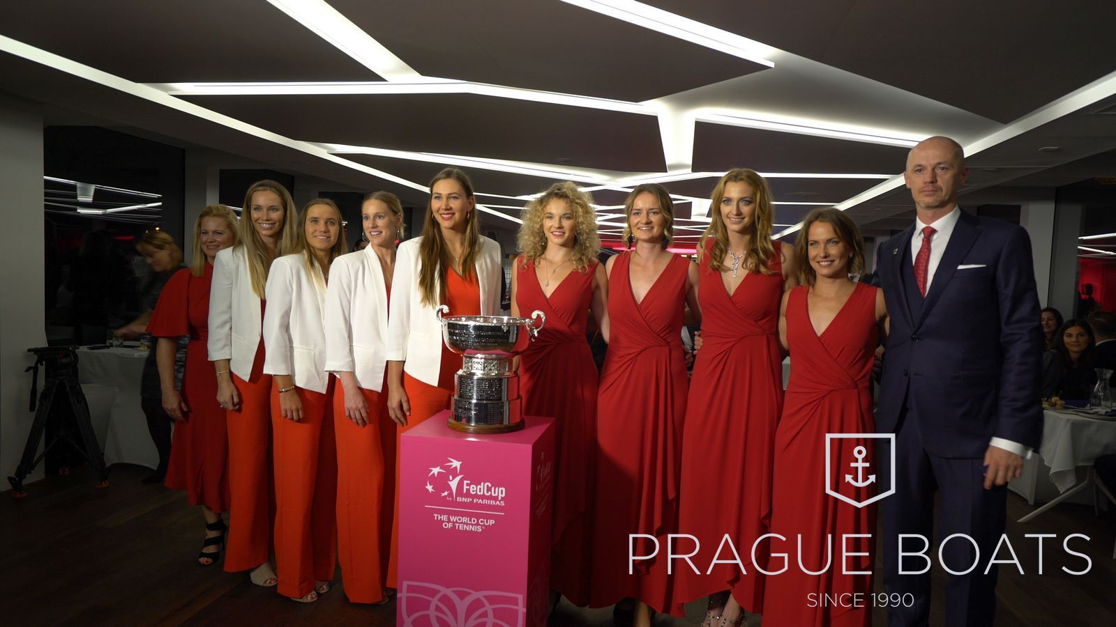 Tenisový tým v červených šatech s trofejí Fed Cup na lodi Grand Bohemia