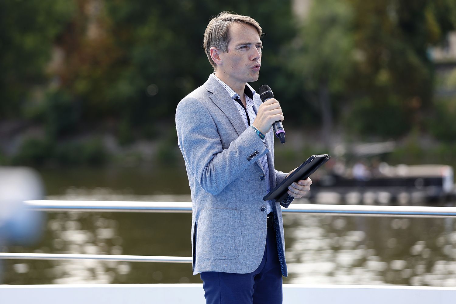 A host with a microphone on the deck of a boat at the Livesport Prague Open event
