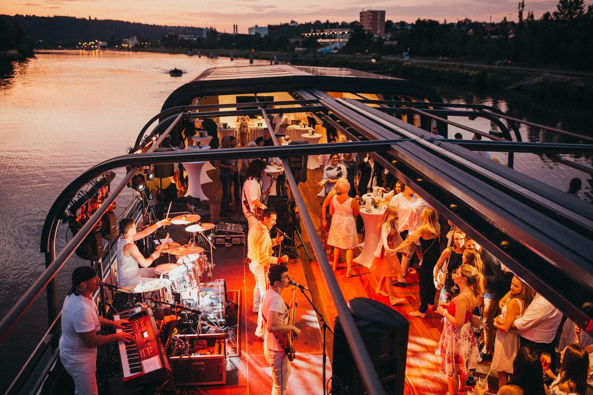Firmenfeier mit Band und Tanz an Deck eines Boots in der Abenddämmerung