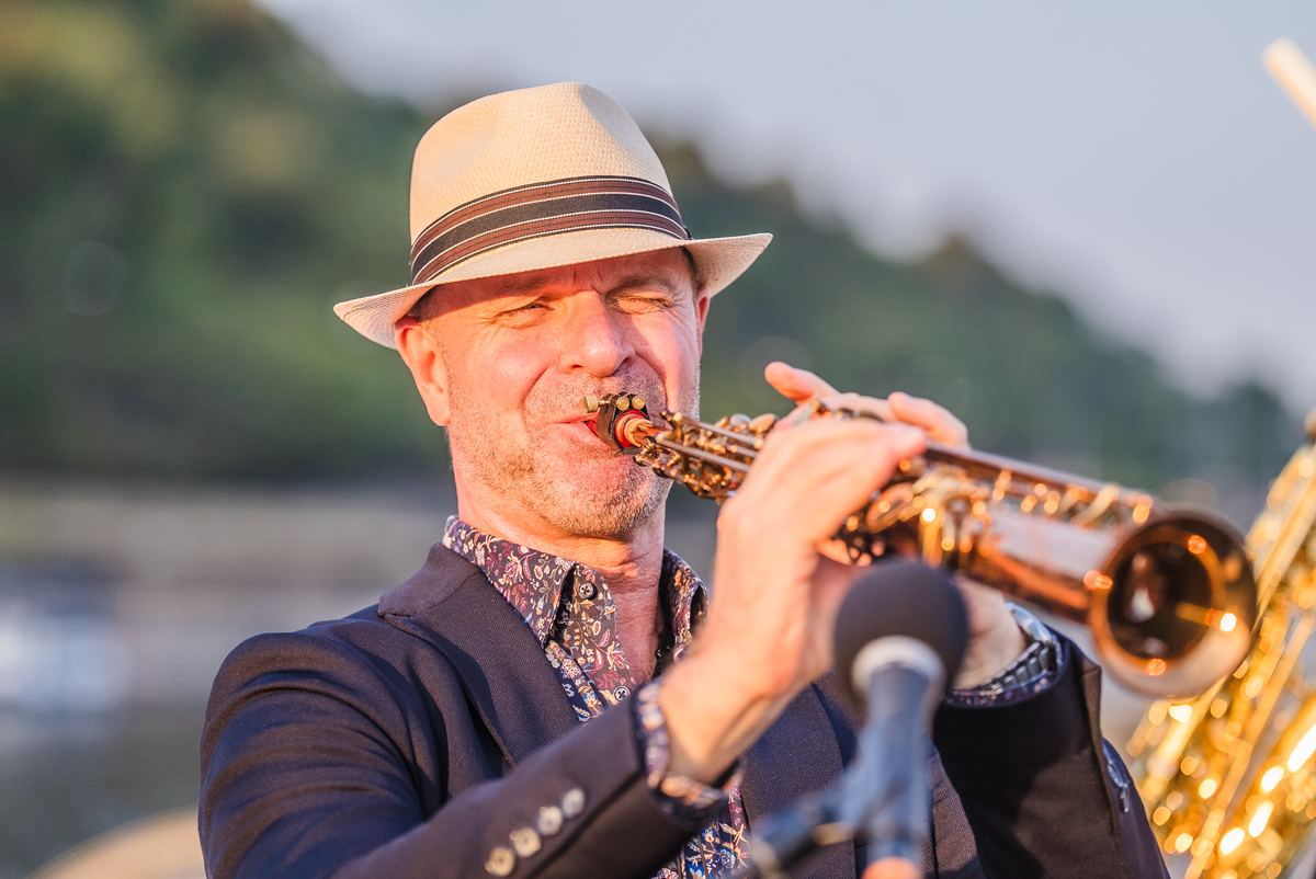 Saxofonist spielt bei Sonnenuntergang auf einem Boot