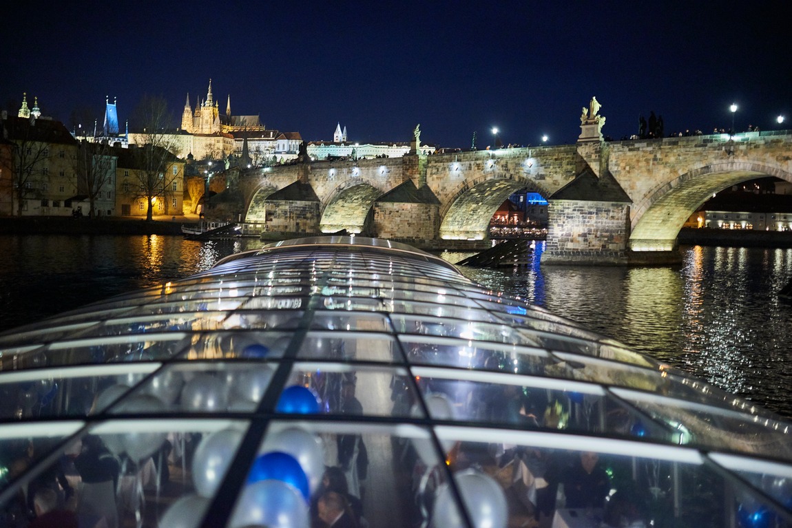 The glass roof at night with Charles Bridge and illuminated Prague Castle behind