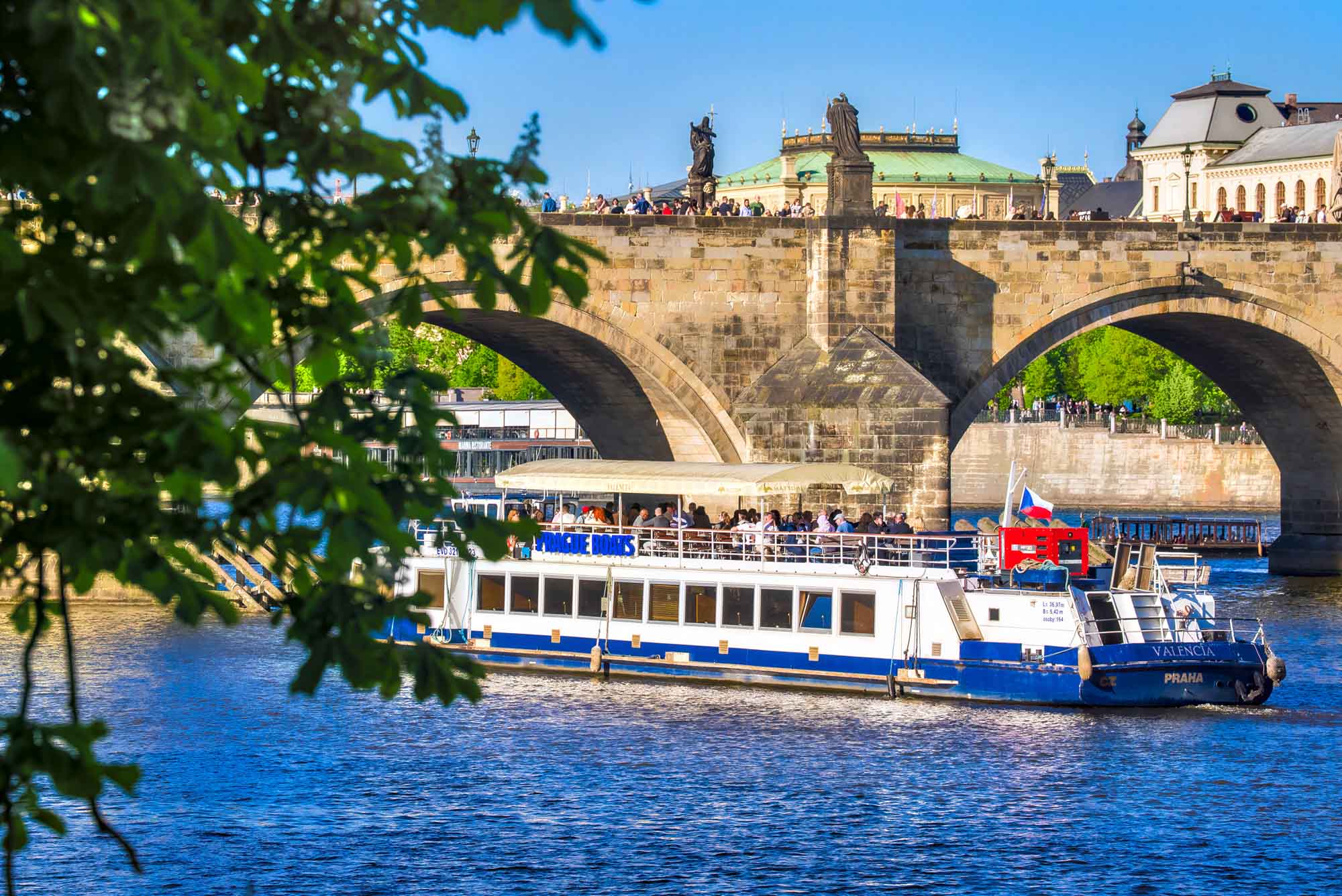 Valencia with guests by Charles Bridge, framed by leaves