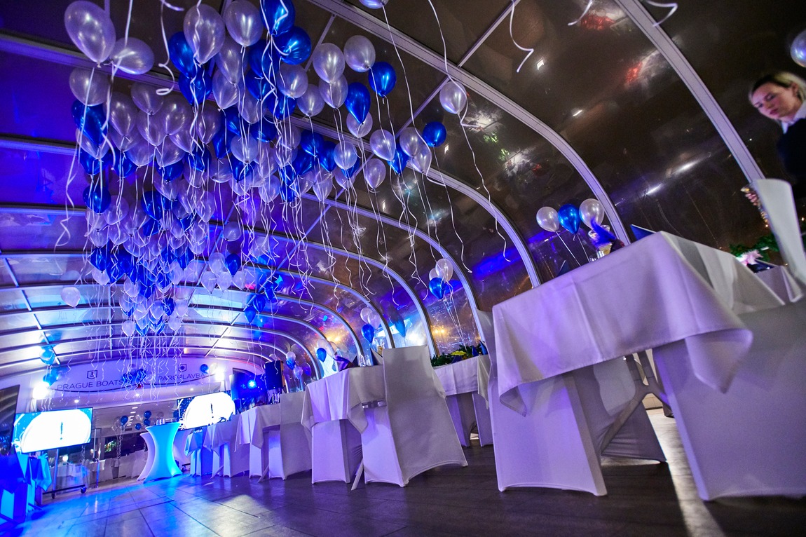 The glass salon lit in blue with balloons and set tables