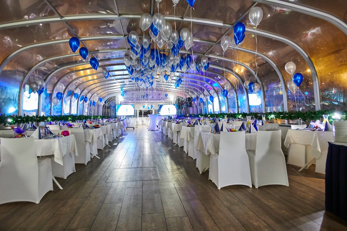 The glass-roofed hall with blue and silver balloons and long tables