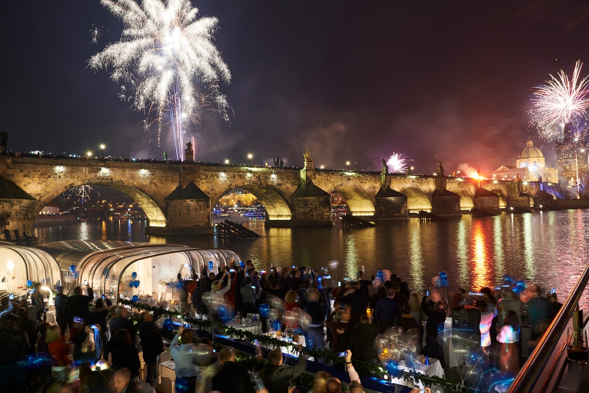 Guests on deck watching the midnight fireworks over Charles Bridge