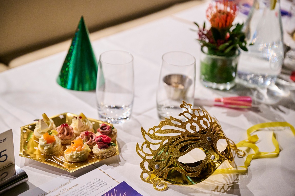 Canapés on a gold tray with a gold mask and a party hat