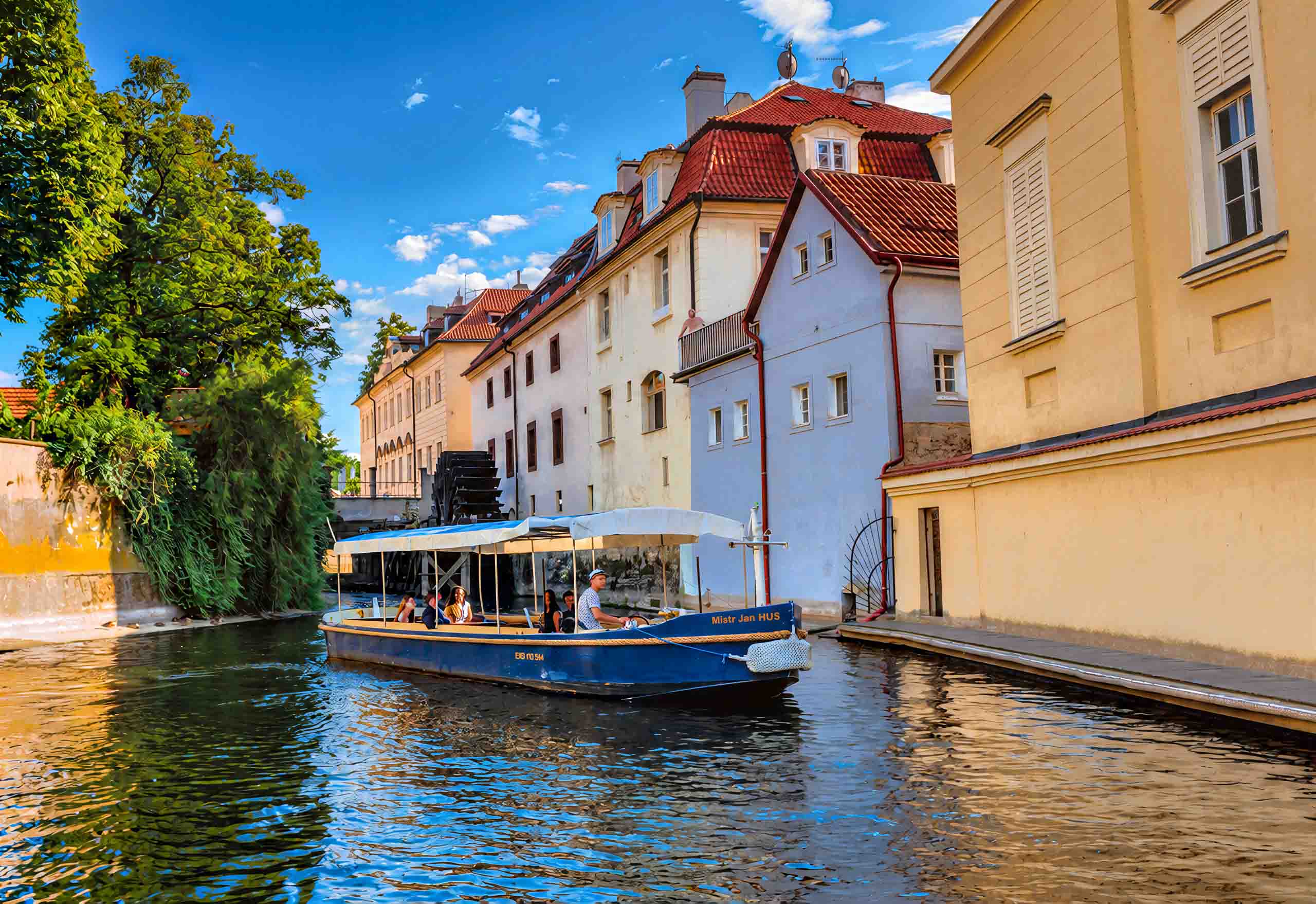 El Mistr Jan Hus con pasajeros en la Čertovka entre casas antiguas
